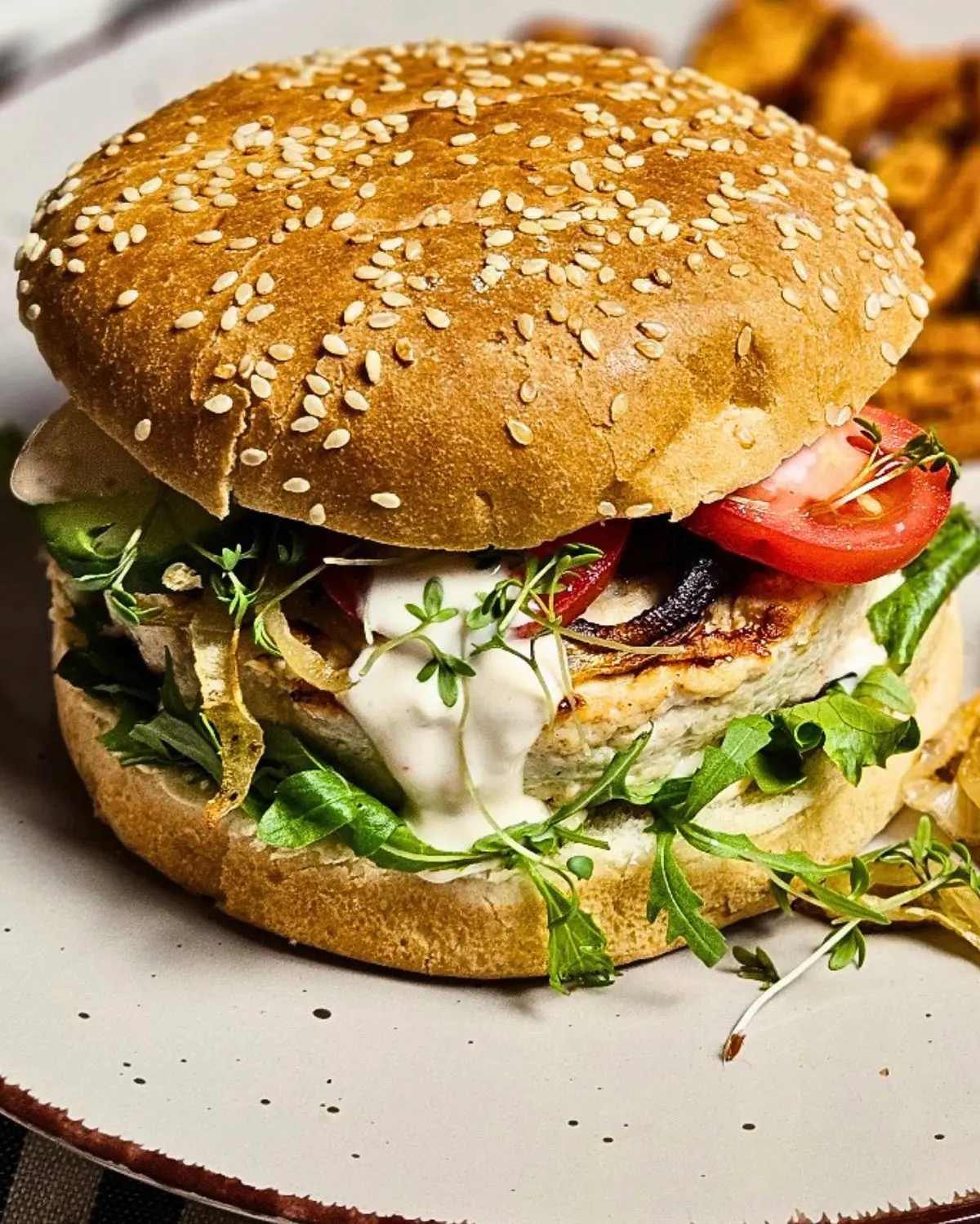 Chickenburger mit Joghurtsauce und karamellisierten Zwiebel auf einem Teller serviert
