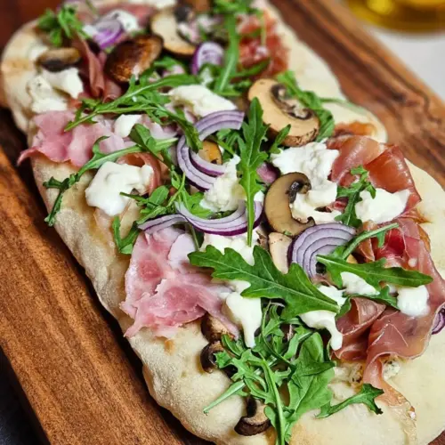 Mediterrane Pinsa mit Schinken, Champignons und Rucola