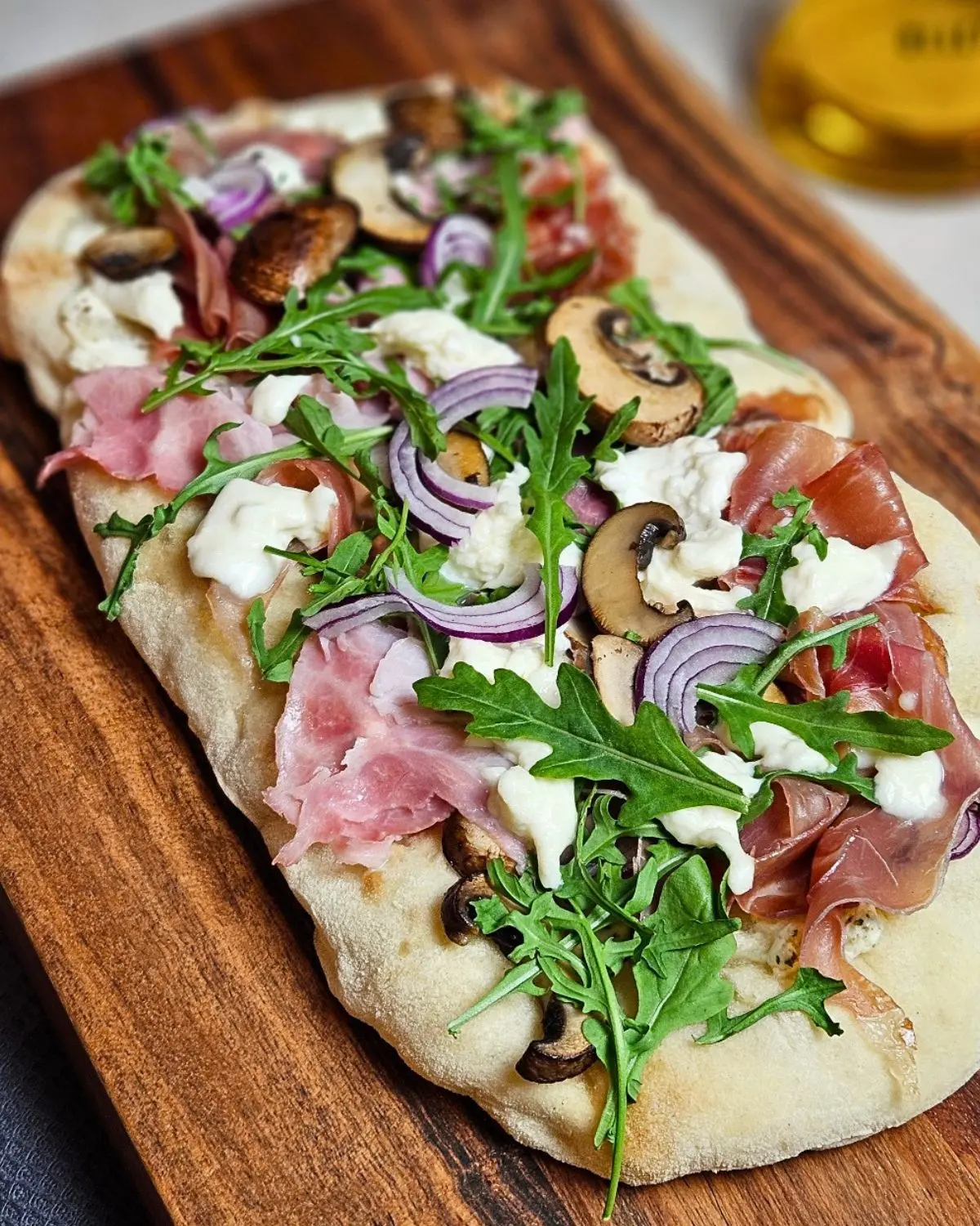 Mediterrane Pinsa mit Schinken, Champignons und Rucola