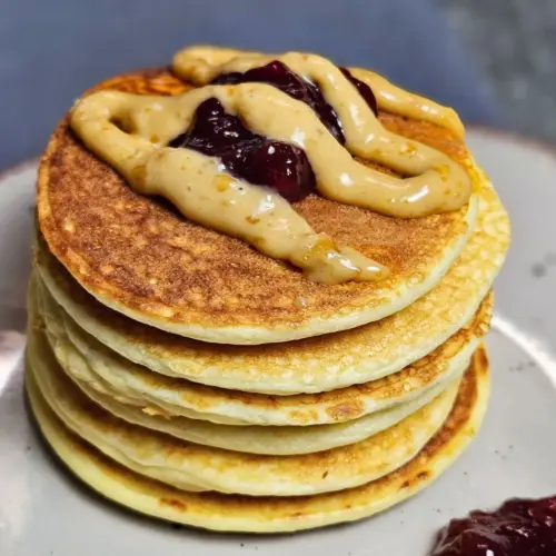 Low Carb Pancakes mit Preiselbeeren und Erdnuss-Topping auf einem Teller angerichtet
