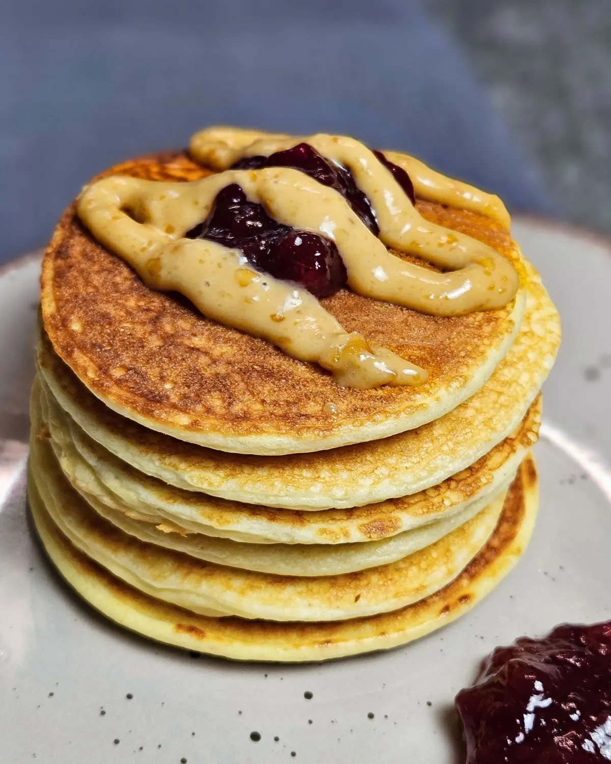 Low Carb Pancakes mit Preiselbeeren und Erdnuss-Topping auf einem Teller angerichtet