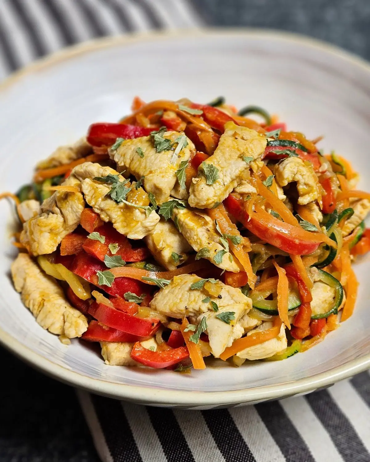 Low Carb Zoodles mit Hähnchen und Erdnusssauce auf einem Teller angerichtet