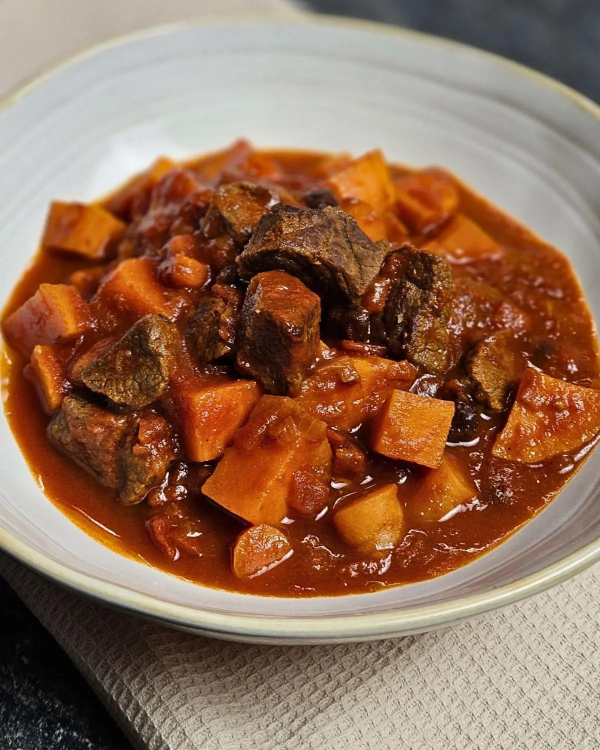 Orientalisches Gulasch mit Süßkartoffeln auf einem Teller angerichtet