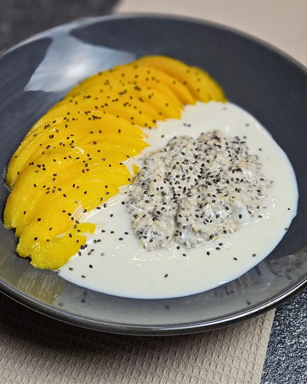 Overnight Oats mit Mango und Protein-Kokos-Creme auf einem Teller angerichtet