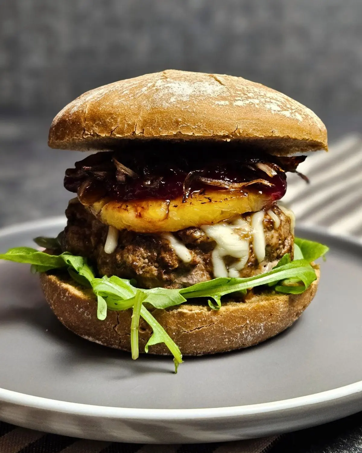 Saftiger Burger mit Rindfleisch, Ananas und Preiselbeeren auf einem Teller angerichtet