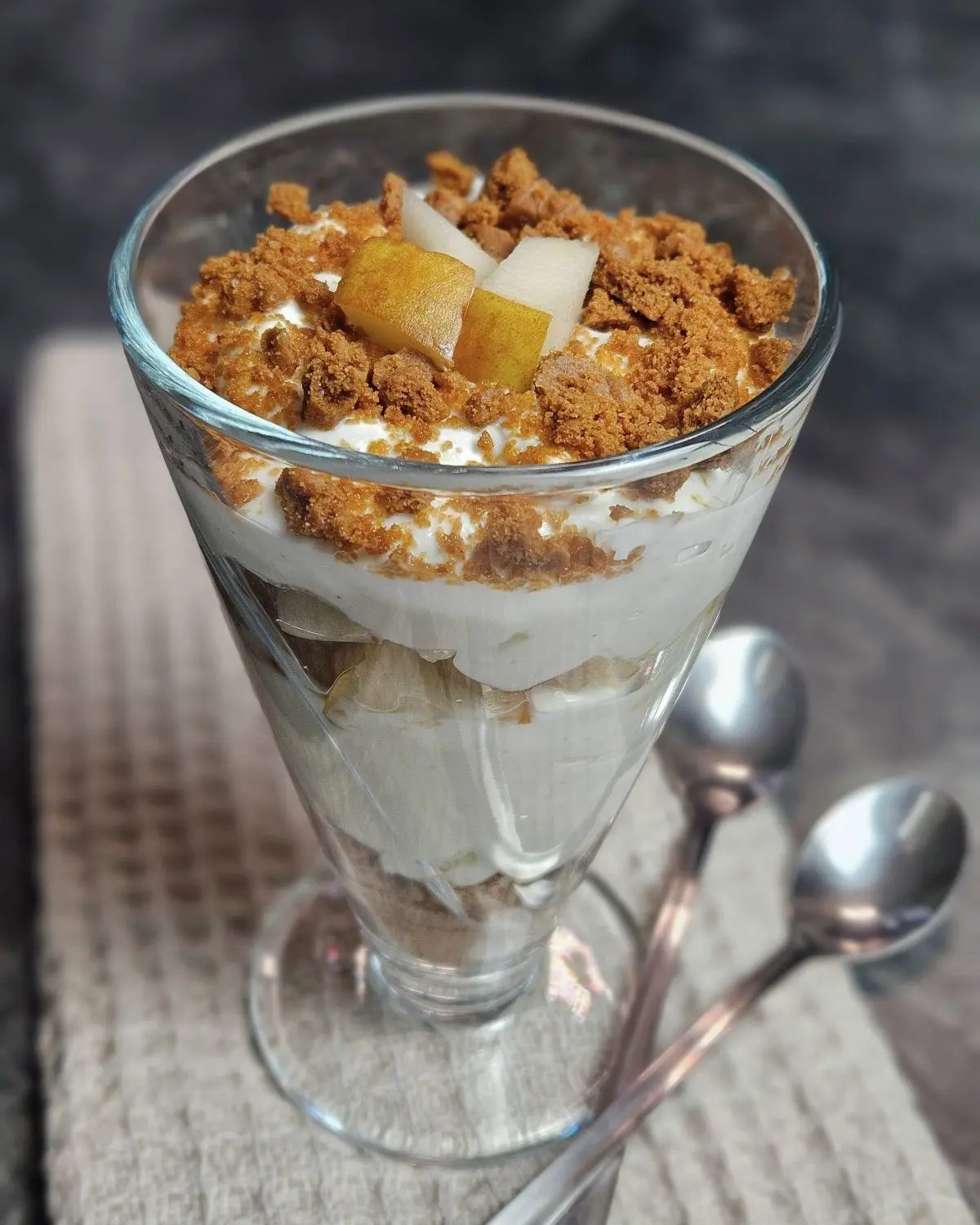 Skyr mit Birne und Karamellcrumble in einem hohen Glas geschichtet