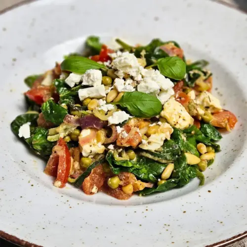 Zoodles mit Feta, Spinat und Erbsen auf einem Teller angerichtet