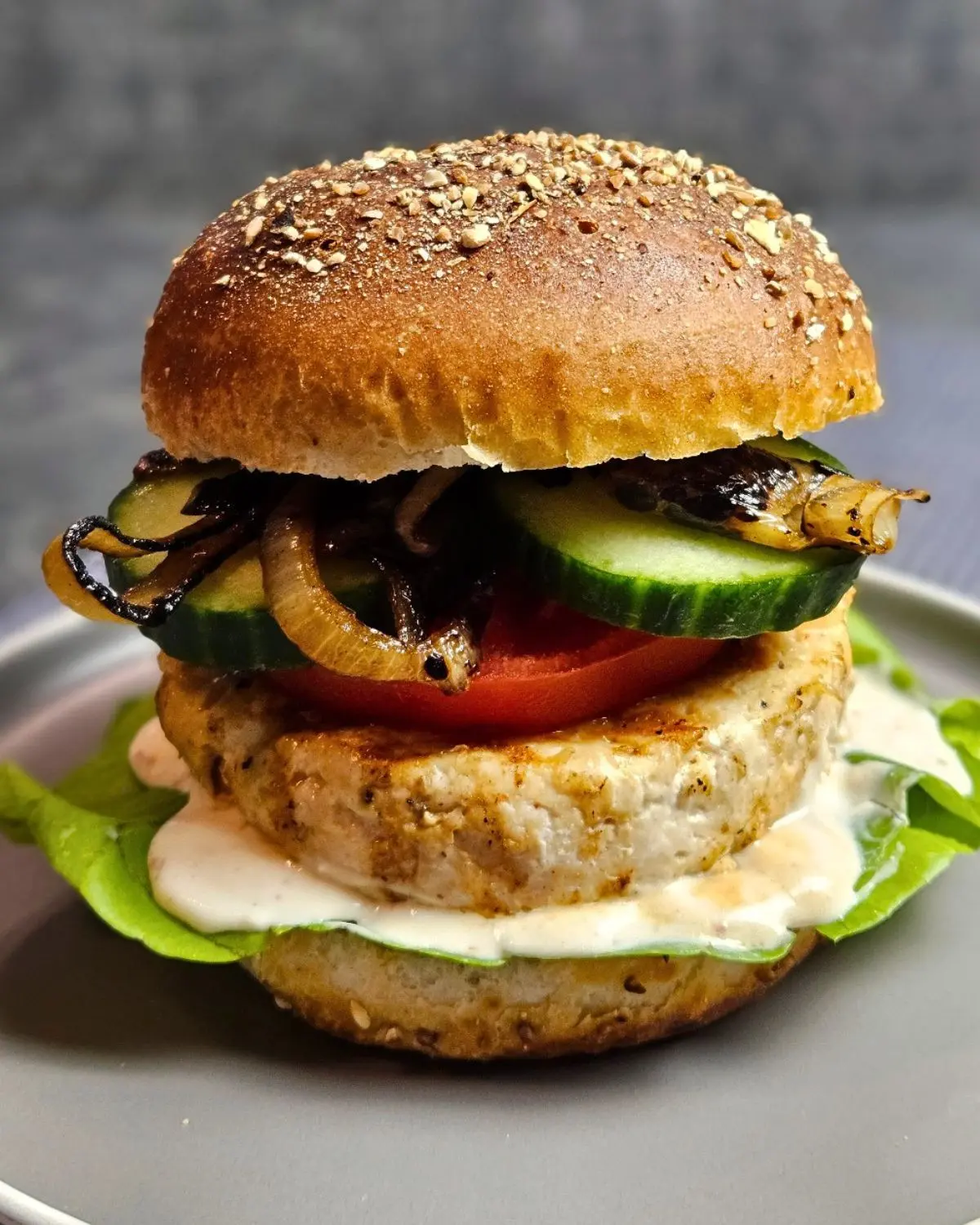 Chickenburger mit karamellisierten Zwiebeln und Joghurtsauce auf einem Teller angerichtet