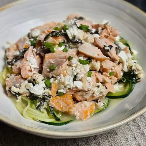 Cremige Zoodles mit Lachs, Spinat und Feta in einer flachen Schüssel angerichtet