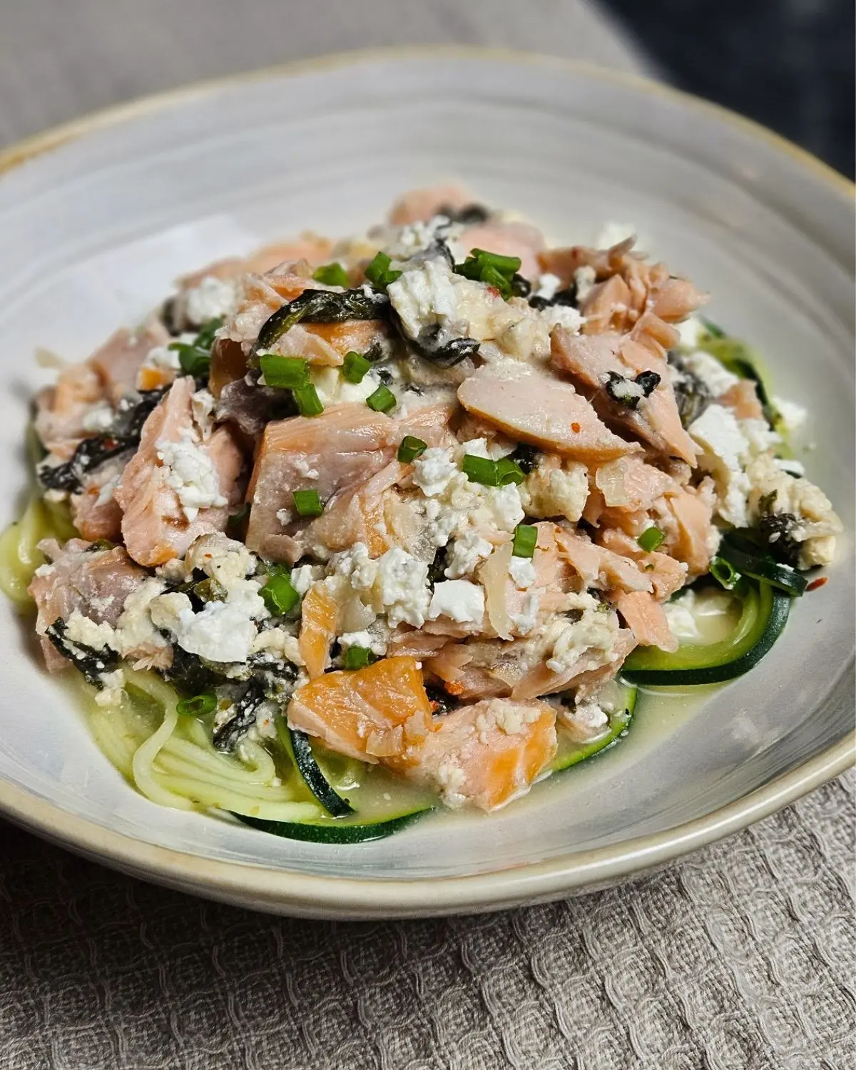 Cremige Zoodles mit Lachs, Spinat und Feta in einer flachen Schüssel angerichtet