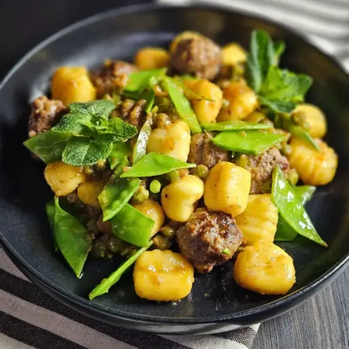 Gnocchi mit Hackfleischbällchen und Erbsen auf einem Teller angerichtet