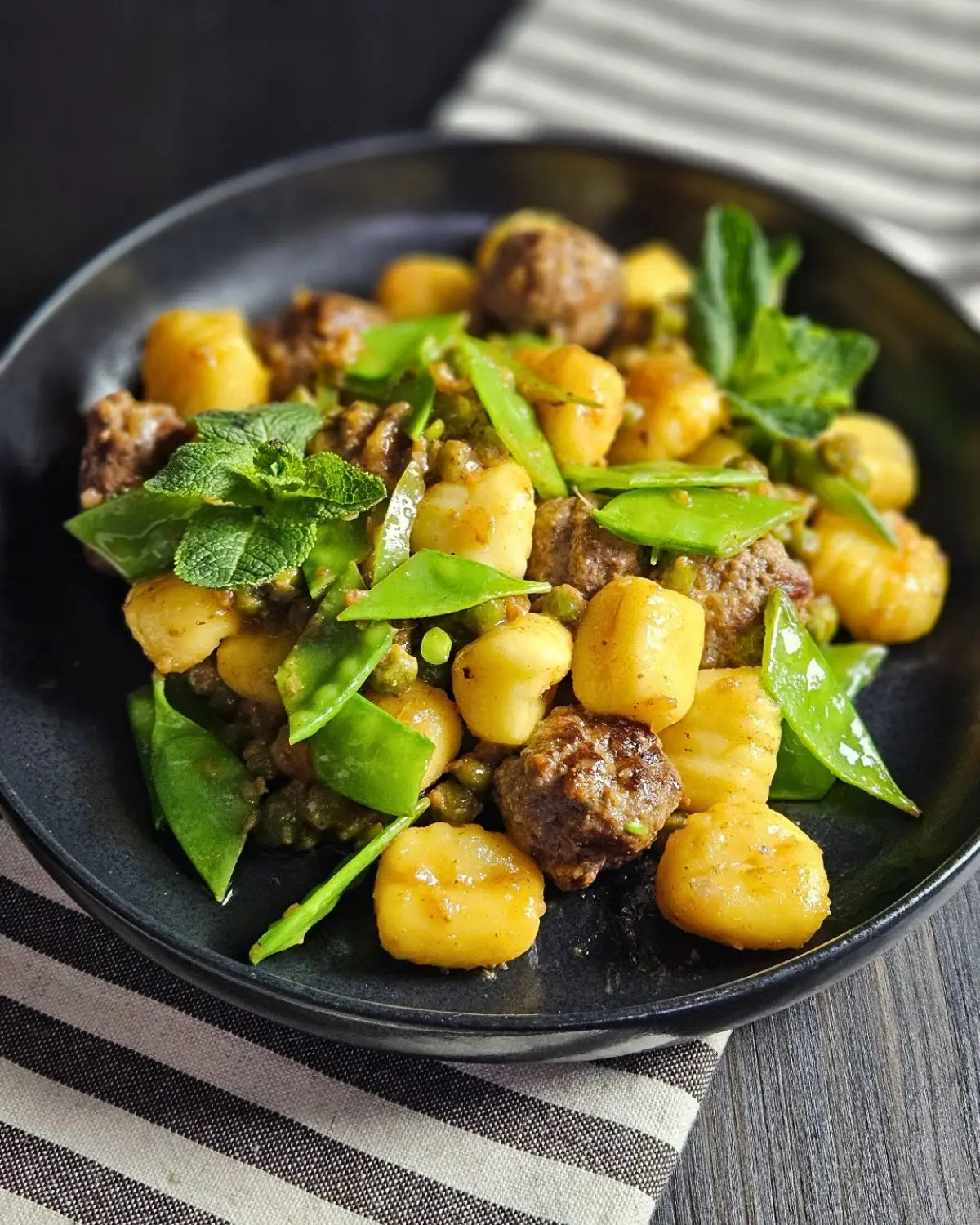 Gnocchi mit Hackfleischbällchen und Erbsen auf einem Teller angerichtet
