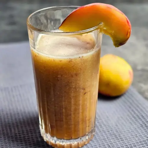 High Protein Pfirsich-Eistee-Shake in einem Glas mit einem Pfirsichstück auf dem Rand