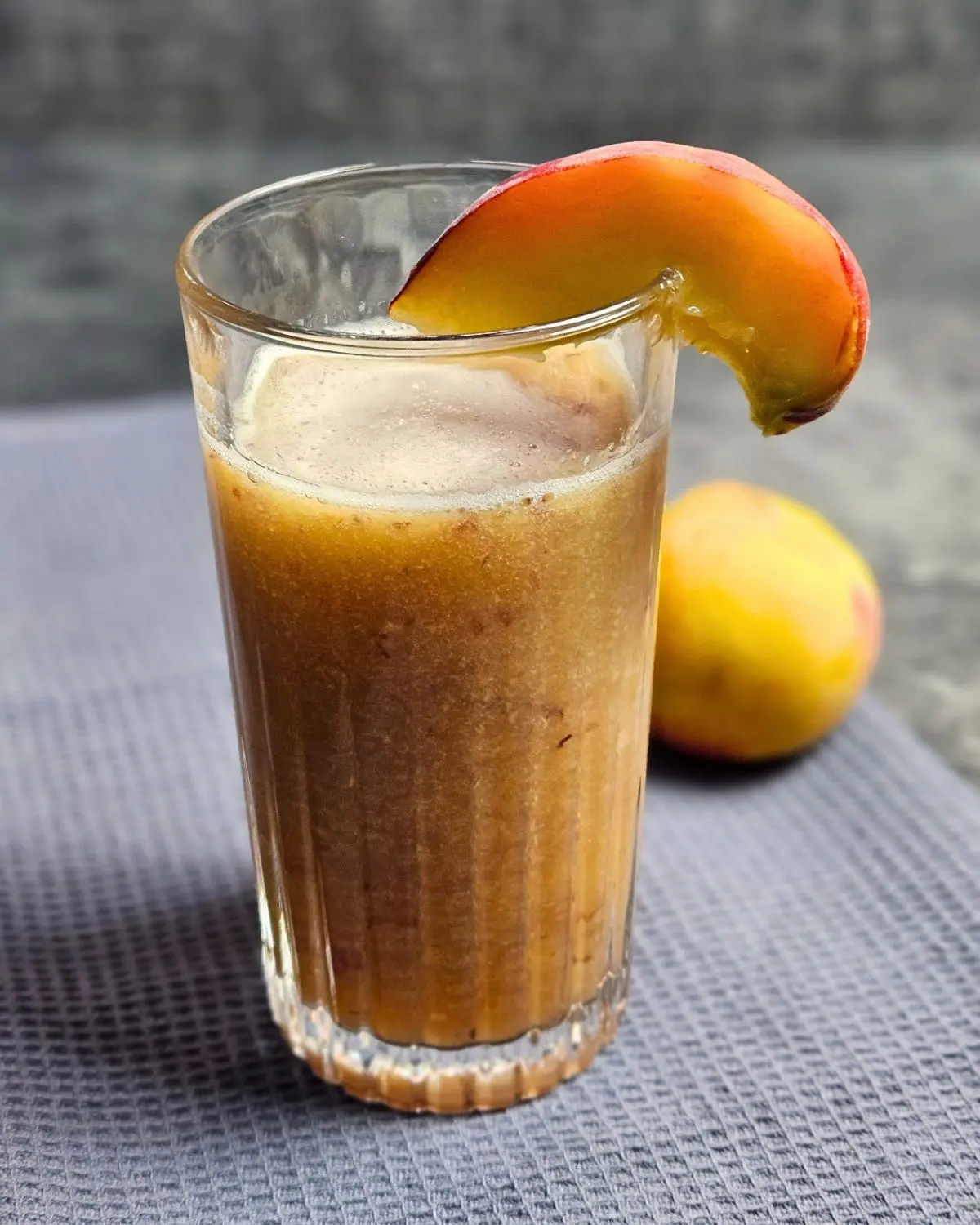 High Protein Pfirsich-Eistee-Shake in einem Glas mit einem Pfirsichstück auf dem Rand