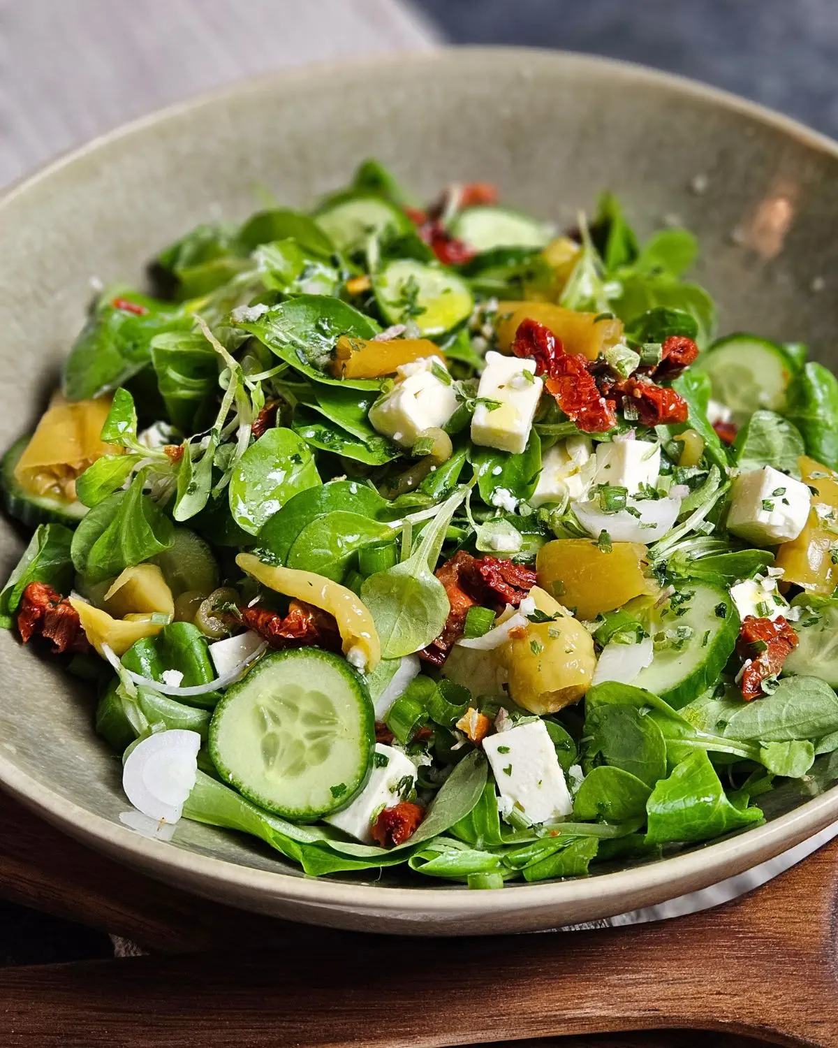 Feldsalat mit Gurke, Feta und getrockneten Tomaten in einer Schüssel angerichtet