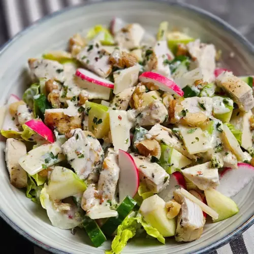 Hähnchen-Apfel-Salat mit Parmesan und Walnüssen in einer Schüssel serviert