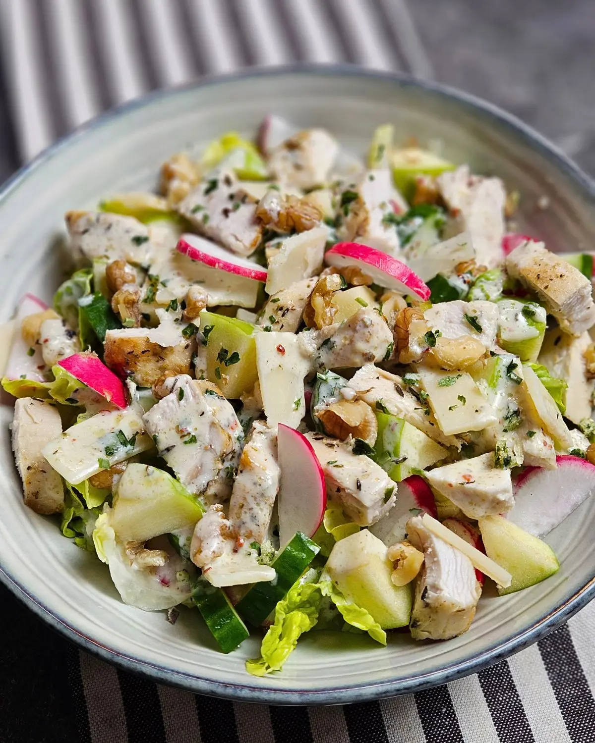 Hähnchen-Apfel-Salat mit Parmesan und Walnüssen in einer Schüssel serviert