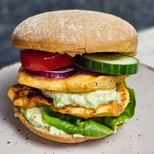 Hähnchenburger mit cremiger Avocado-Skyr-Sauce auf einem Teller angerichtet