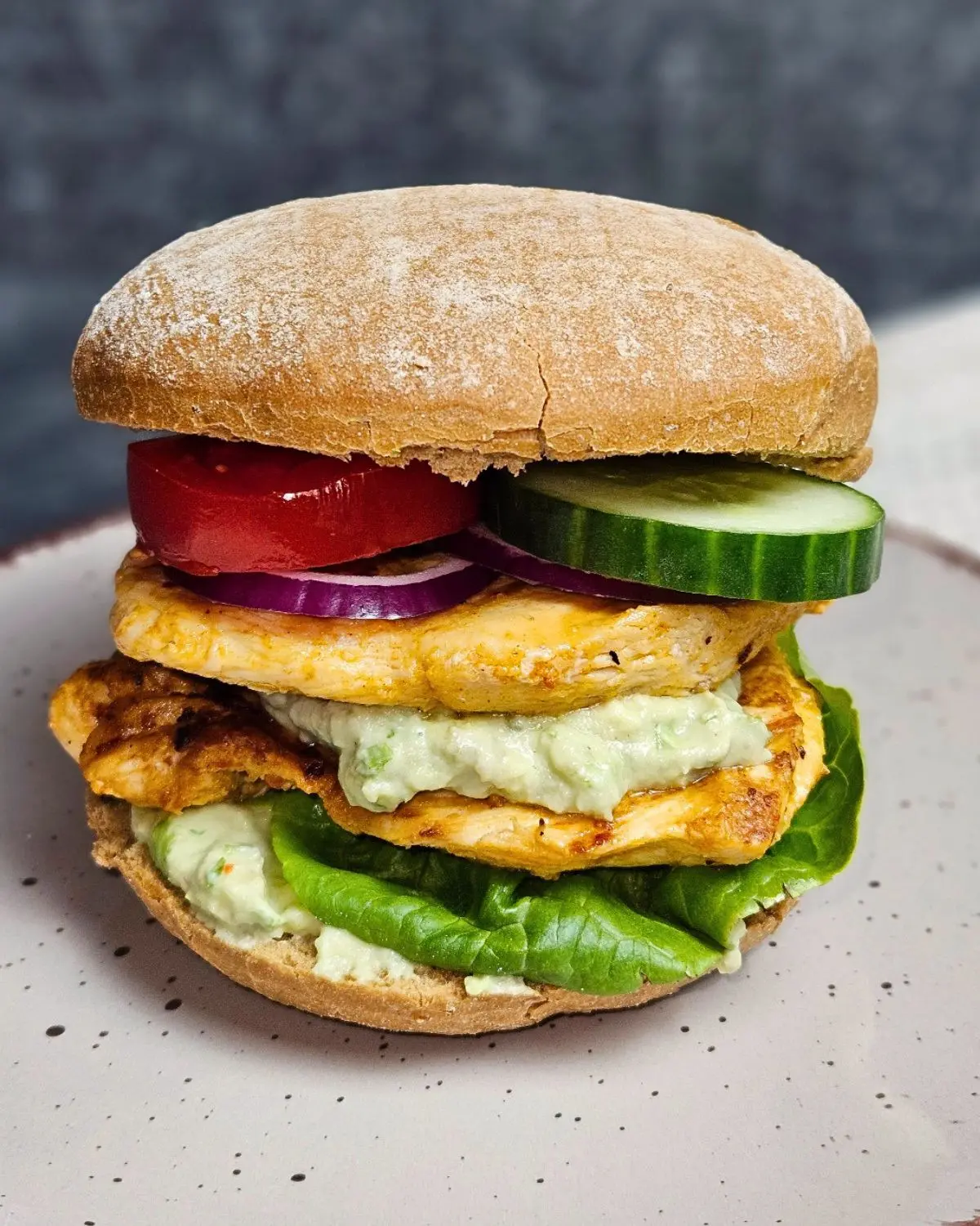Hähnchenburger mit cremiger Avocado-Skyr-Sauce auf einem Teller angerichtet