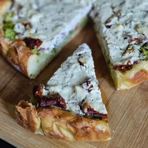High Protein Brokkoli-Quiche mit Quarkteig angeschnitten auf einem Brett angerichtet