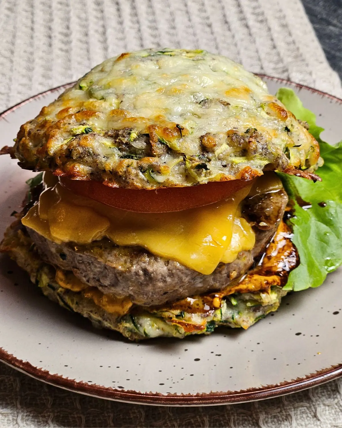 Low Carb Burger mit Zucchini-Käse-Bun auf einem Teller angerichtet