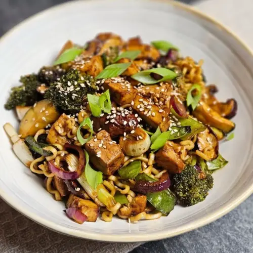 Asiatischer Tofu mit Gemüse und Mie-Nudeln auf einem Teller angerichtet