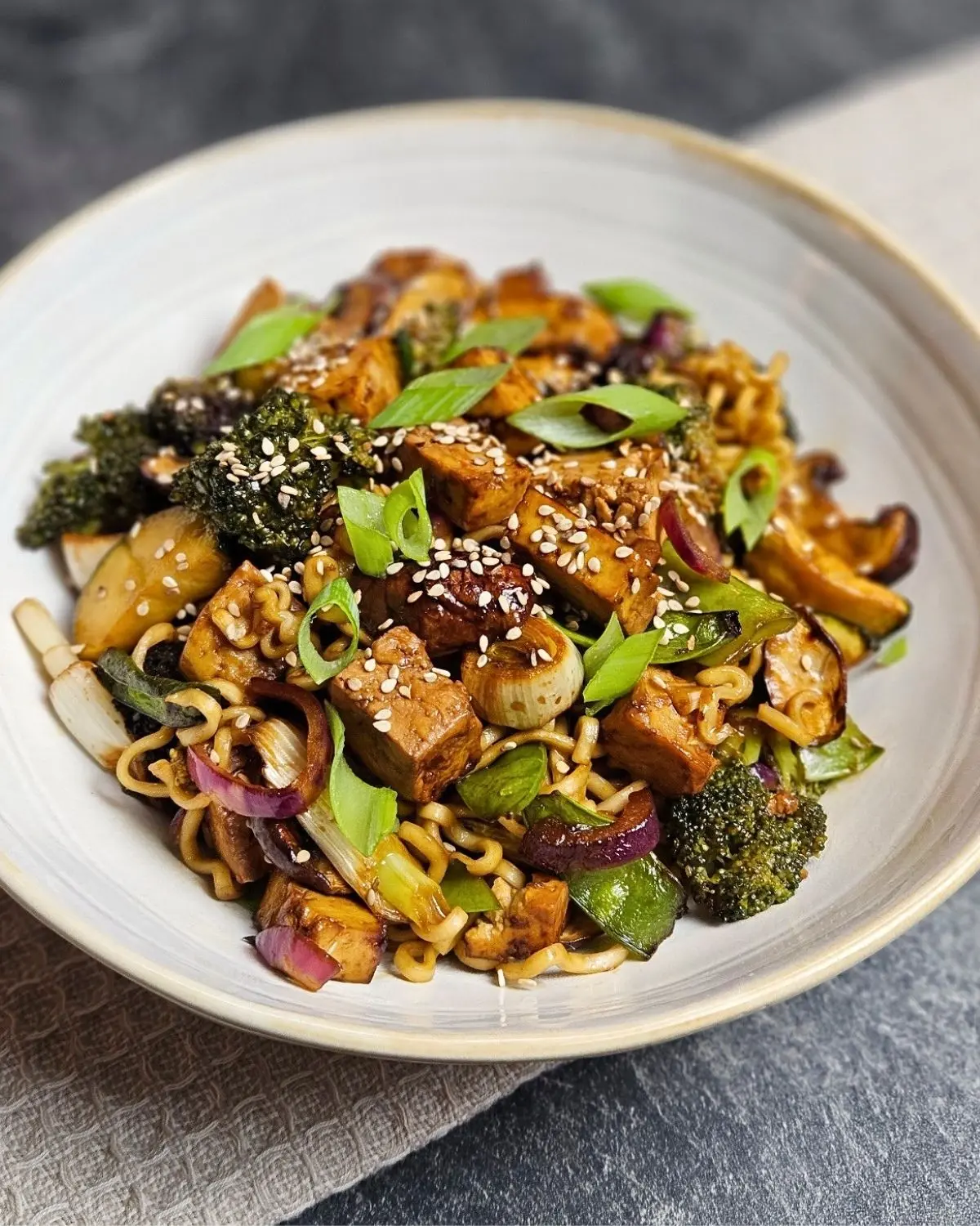 Asiatischer Tofu mit Gemüse und Mie-Nudeln auf einem Teller angerichtet