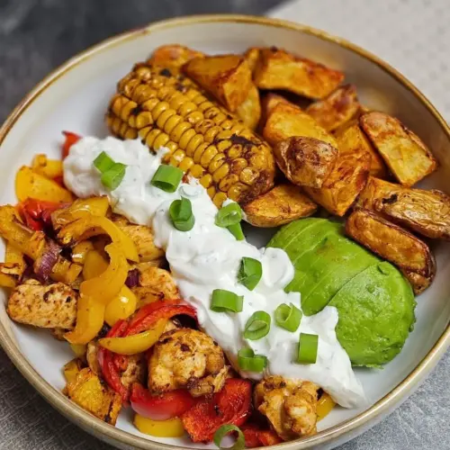 Hähnchen-Fajita Bowl mit Mais, Avocado und Kartoffelecken in einer Bowl angerichtet