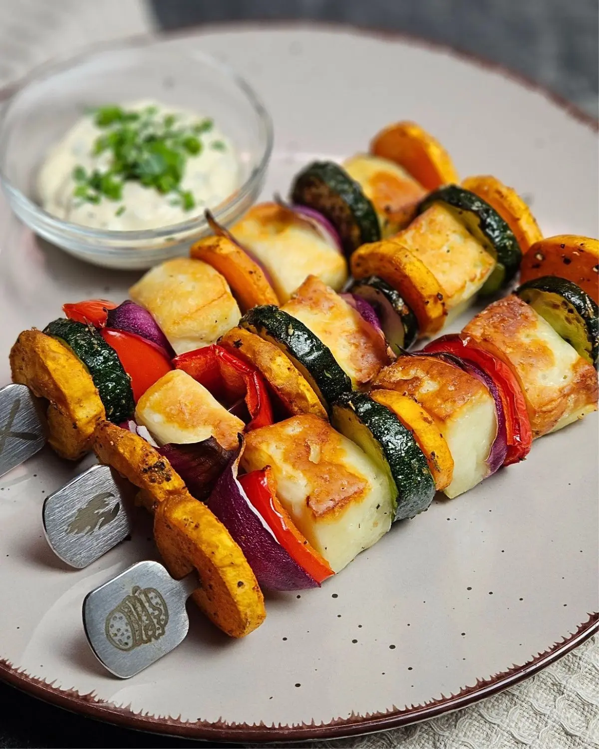 Halloumi-Süßkartoffel-Spieße mit Frischkäse-Petersilie-Dip - Airfryer Edition, drei Spieße mit einem Schälchen Sauce auf einem Teller angerichtet