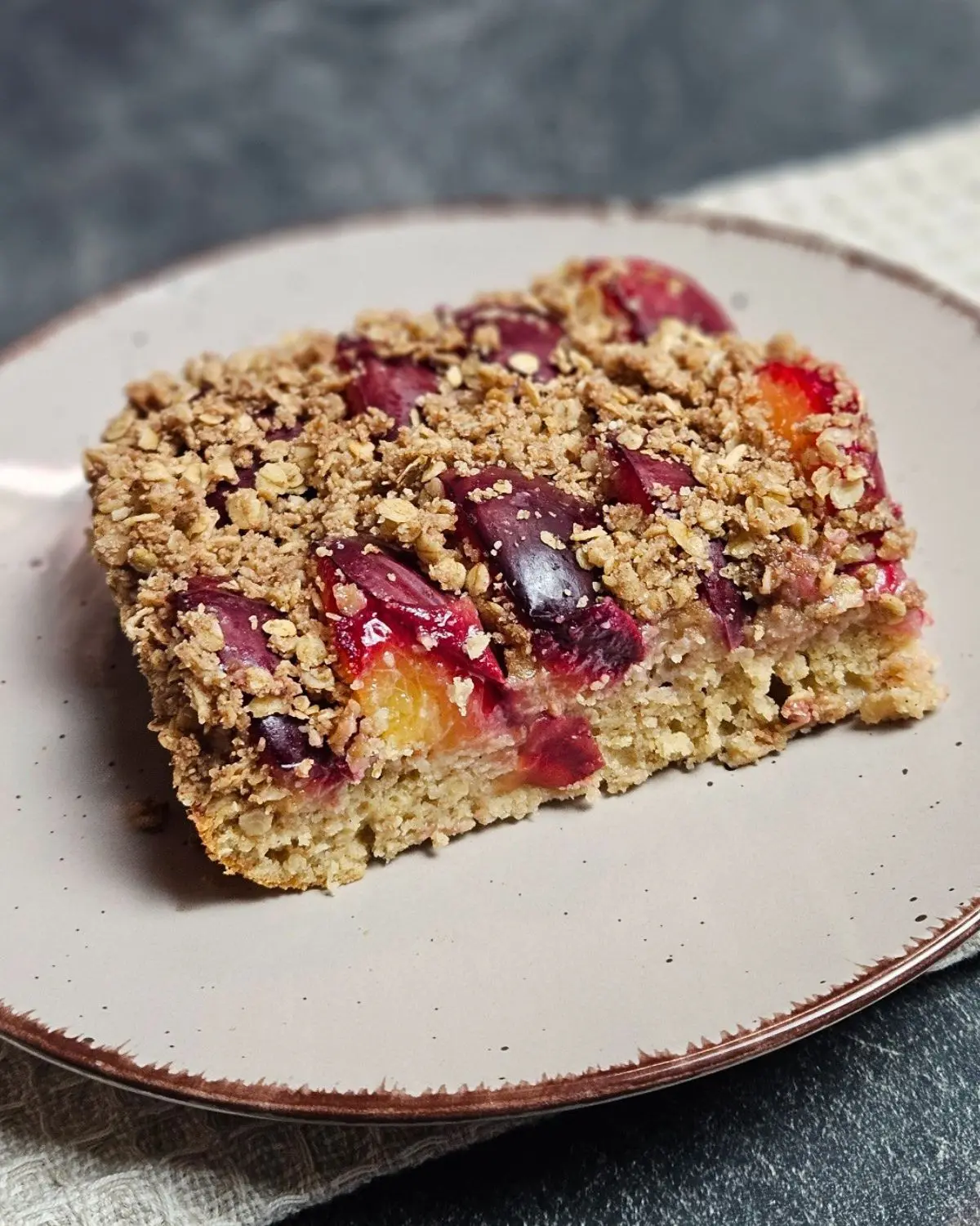 Ein Stück High Protein Zwetschgenkuchen mit Haferflockenstreusel auf einem Teller angerichtet