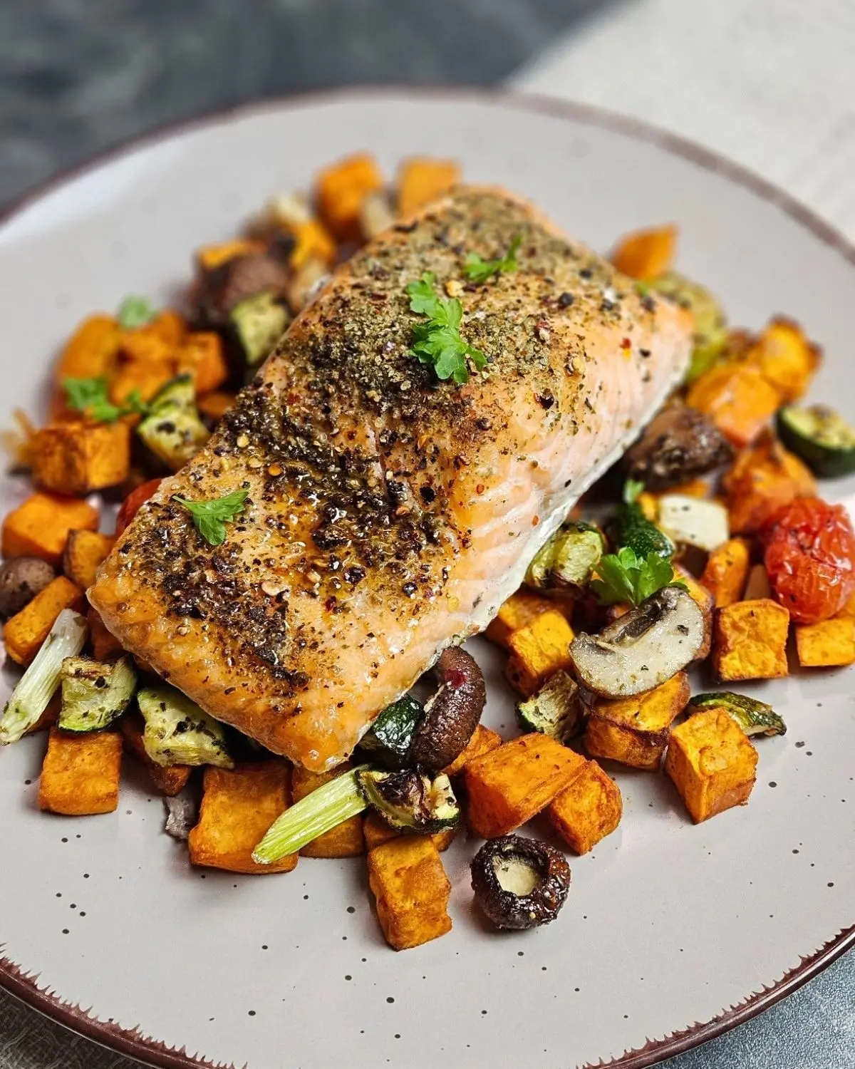 Mediterraner Lachs mit Süßkartoffeln und Gemüse auf einem Teller angerichtet