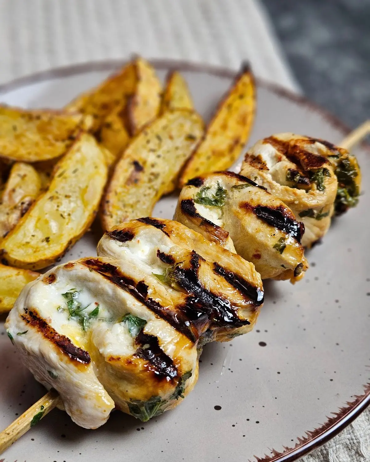 Putenröllchen mit Frischkäse, Feta und Aprikose mit Kartoffelecken auf einem Teller angerichtet