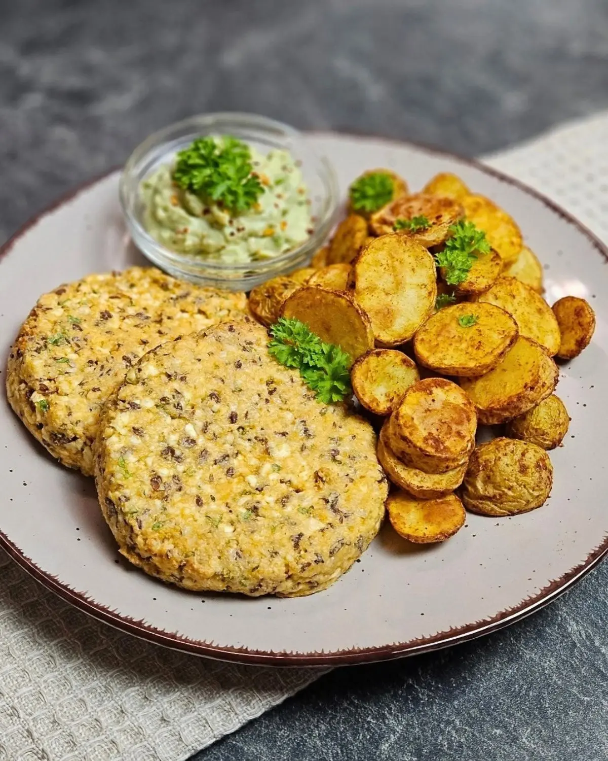 Frischkäsetaler mit Avocado-Dip und Bratkartoffeln aus dem Airfryer auf einem Teller angerichtet