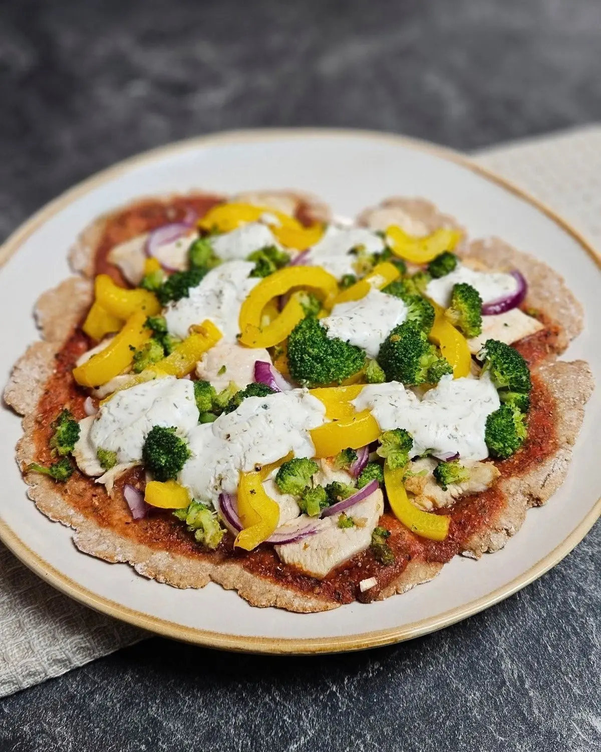 High Protein Chicken Pizza mit Skyr-Teig auf einem Teller angerichtet